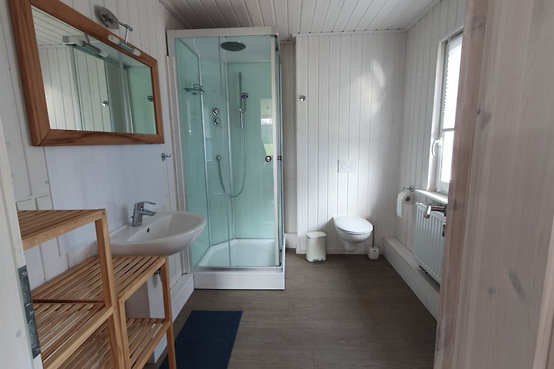 Badezimmer mit Badewanne, Spiegel, Dusche und Fenster.