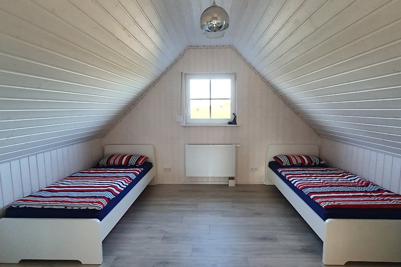 Schlafzimmer mit Bett, Fenster und Holzdecke.