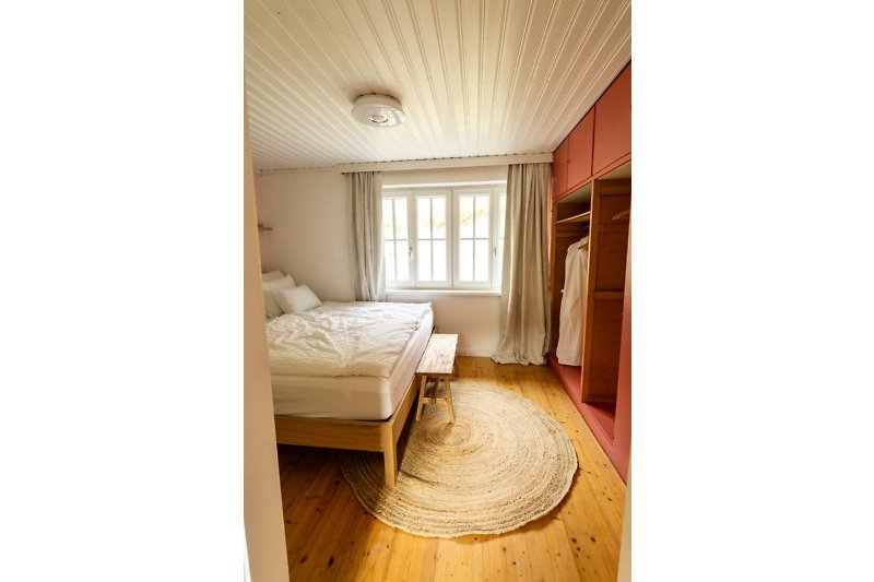 Schlichtes Schlafzimmer mit Holzmöbeln und gemütlicher Bettwäsche.