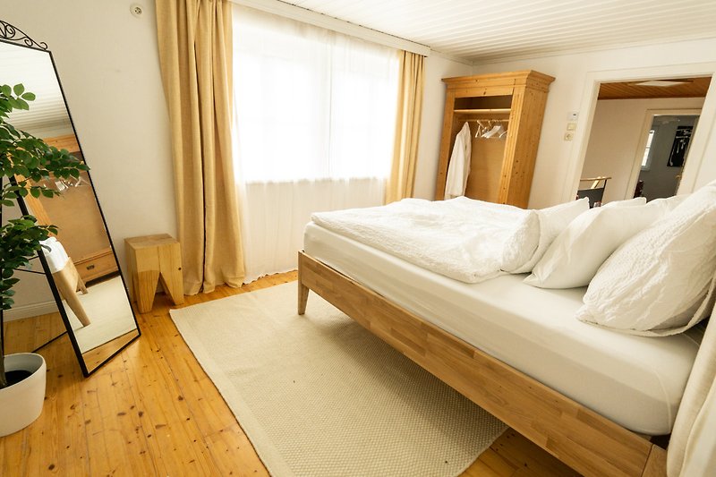 Schlafzimmer mit Holzmöbeln, Bett und Blumentopf.