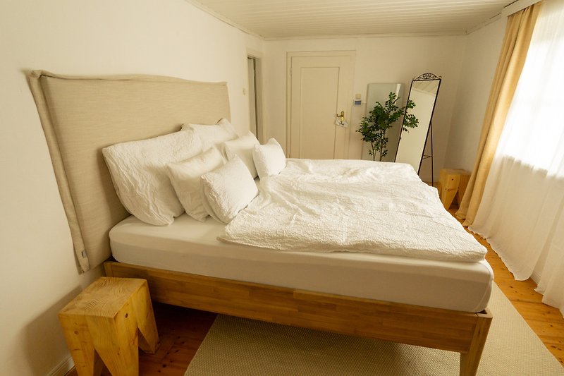 Schlafzimmer mit Holzmöbeln, Bett und Vorhängen.