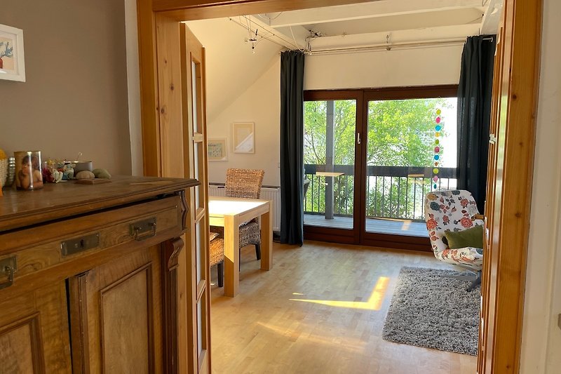 Blick von der Küche ins Wohnzimmer mit Esstisch, Schlafsofa und Ausgang zur Loggia