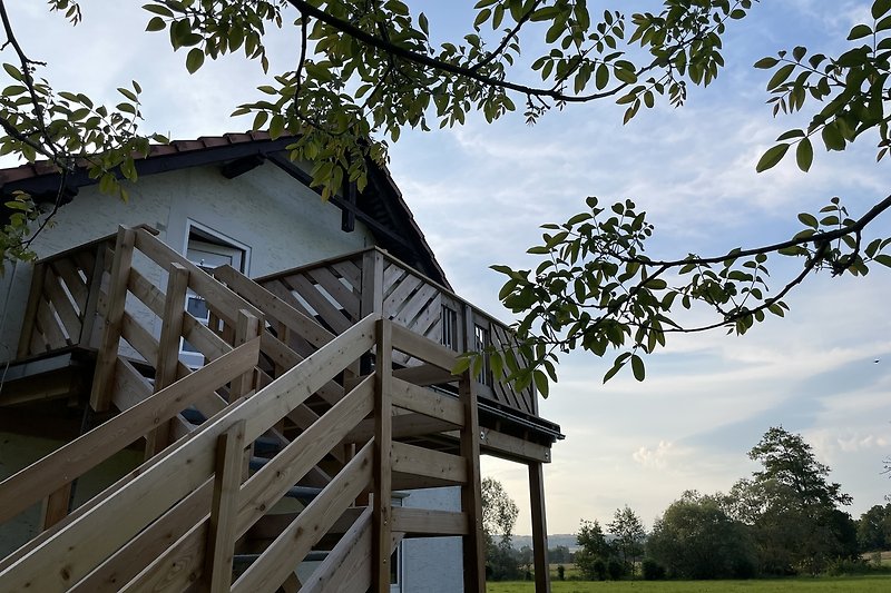 Fachwerkhaus mit Holzverkleidung, grüner Rasen und blauer Himmel.