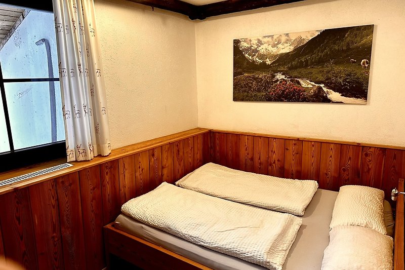 Schlafzimmer mit gemütlichem Bett, Lampen und Vorhängen.