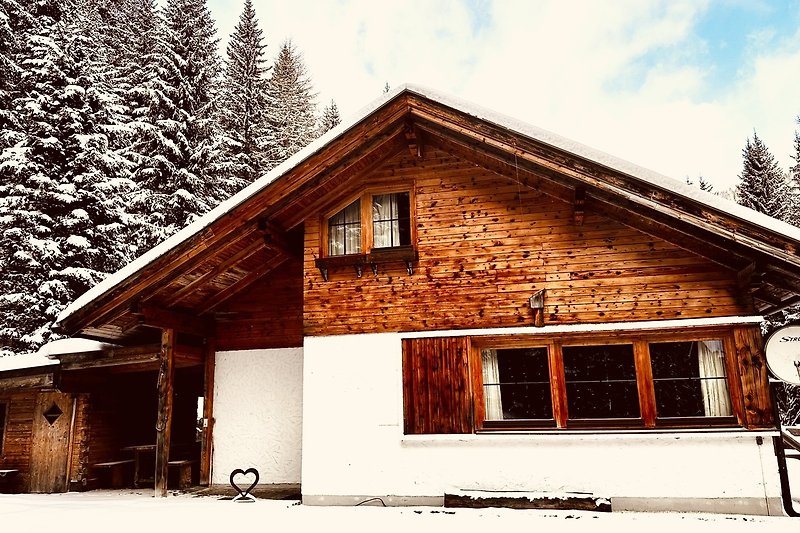 Winterlandschaft mit Holzhütte, Schnee und Tannen. Gemütliches Ferienhaus.
