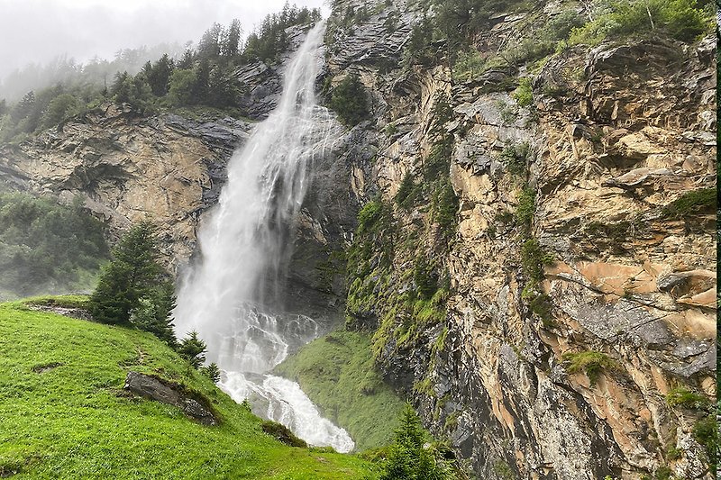 Bergiges Paradies mit Wasserfall, Fluss und grüner Landschaft.