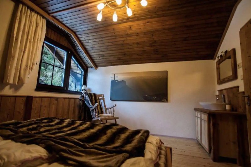 Wohnzimmer mit Fernseher, Holzbalken und gemütlicher Einrichtung.
