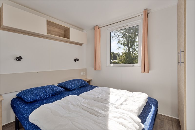 Gemütliches Schlafzimmer mit Holzbett, Fenster und Decke. Gemütliche Bettwäsche.