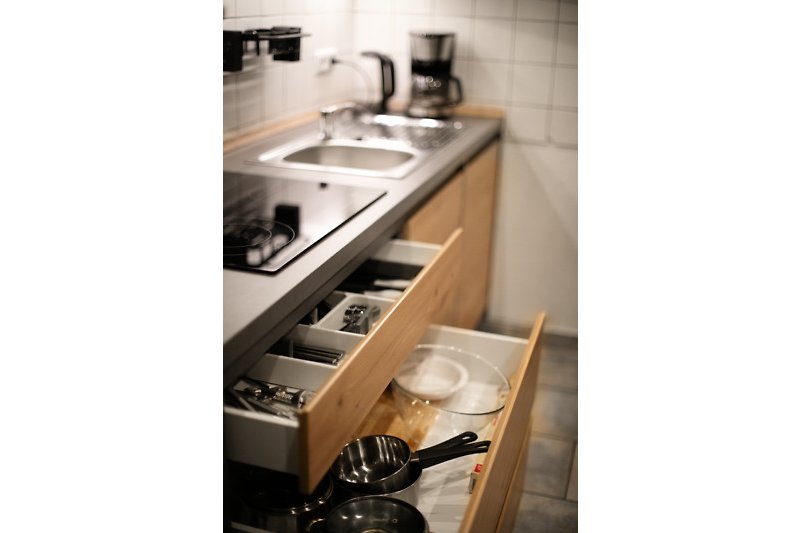 Moderne Küche mit Holzregalen, Küchenspüle und Gasherd.
