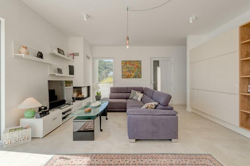 Modernes Wohnzimmer mit grauem Sofa, Holzmöbeln und Lampen. Gemütliche Einrichtung.