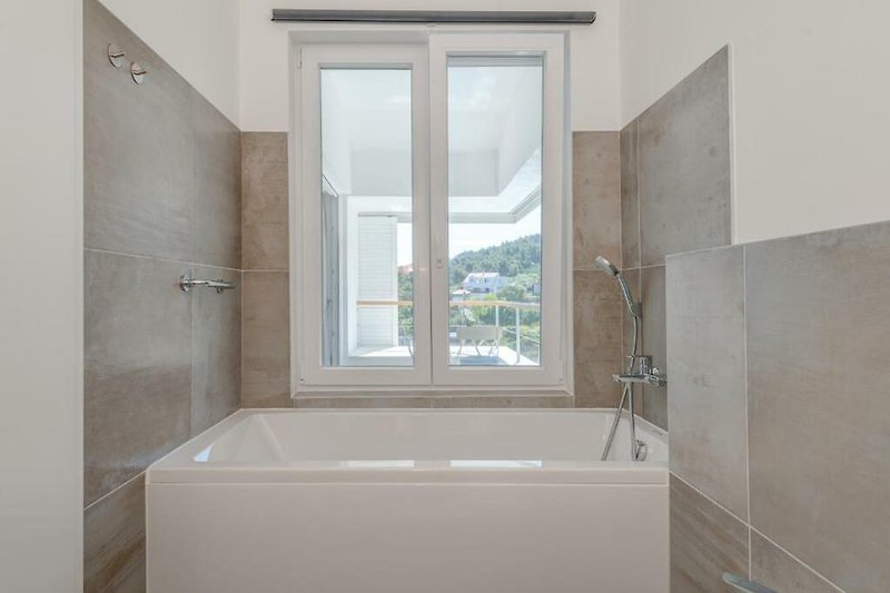 Modernes Badezimmer mit Badewanne, Armaturen und Fliesen. Zeitgemäßes Design.