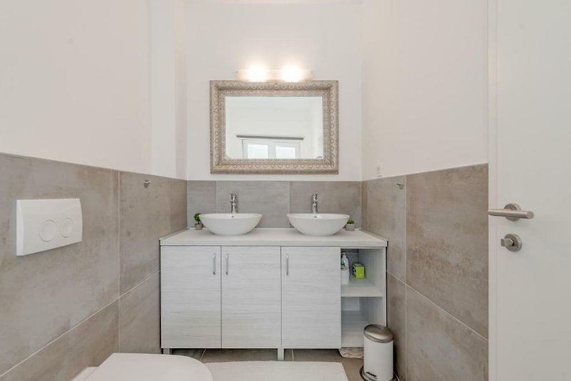 Modernes Badezimmer mit Spiegel, Waschbecken und Armaturen. Zeitgemäßes Design.