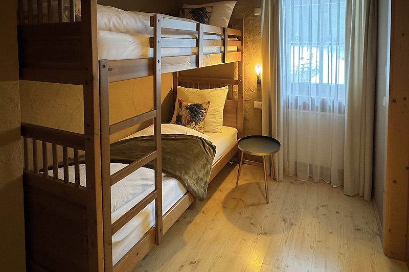 Schlafzimmer mit Holzmöbeln, Bett und Vorhängen.