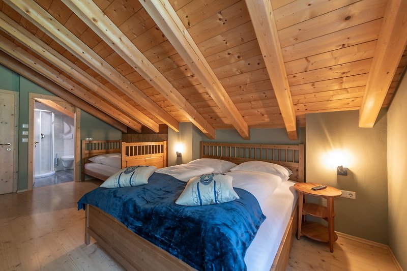 Holzschlafzimmer mit Bett, Decke und Lampe.