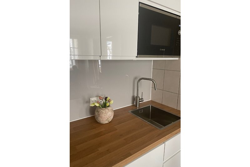 Moderne Küche mit Holzschrank, Spüle und Fenster.