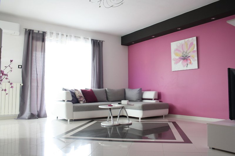 Stilvolles Wohnzimmer mit lila Akzenten und gemütlicher Couch.