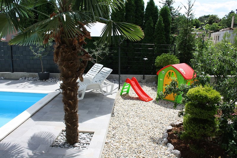 Tropischer Garten mit Pool und Palmen.
