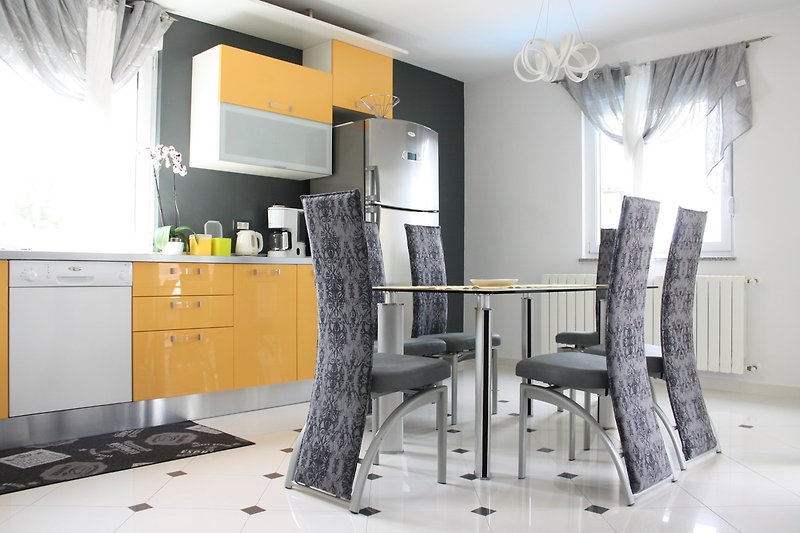 Moderne Küche mit grauen Schränken, Holzarbeitsplatte und Küchengeräten.