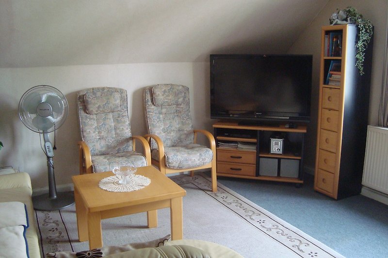 Wohnzimmer mit Fernseher, Couch und Tisch. Gemütliche Einrichtung.