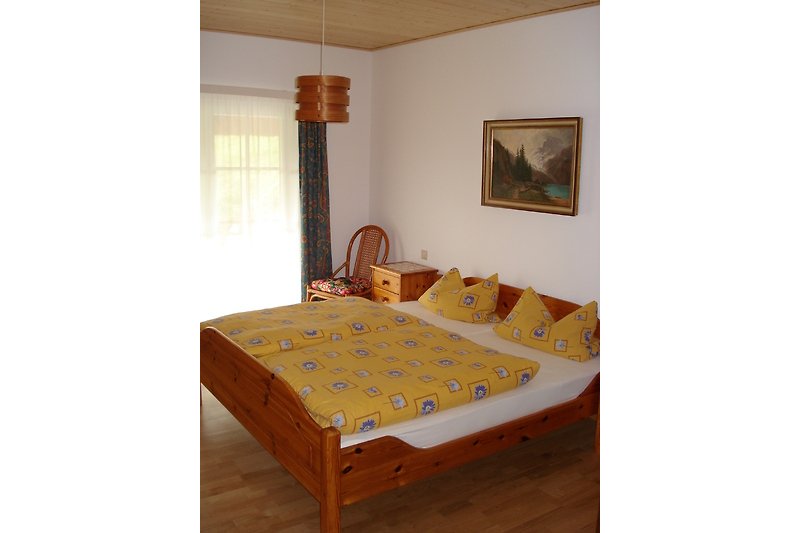 Schlafzimmer mit bequemem Bett, Holzmöbeln und gemütlicher Beleuchtung.