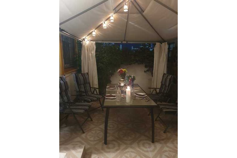 Tisch und Stühle unter schattigem Zelt im Freien.
