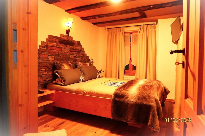 Stilvolles Schlafzimmer mit Holzbett, Kissen und Lampe. Gemütliche Beleuchtung!