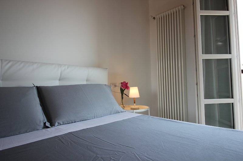 Komfortables Schlafzimmer mit Holzmöbeln und grauen Textilien.
