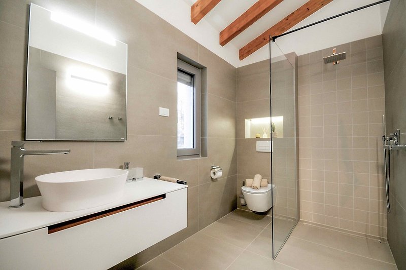 Modernes Badezimmer mit Spiegel, Armatur und Dusche.