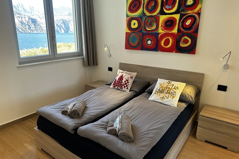 Schlafzimmer mit gemütlichem Bett, Lampen und Kunst an der Wand.