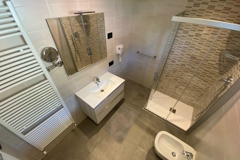 Modernes Badezimmer mit Glasdusche, Spiegel und Keramik.