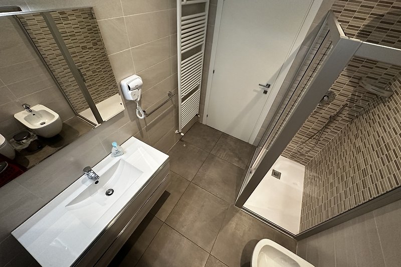 Modernes Badezimmer mit Spiegel, Aluminiumarmaturen und Keramik.