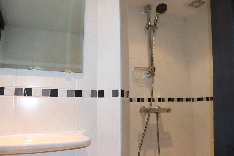 Modernes Badezimmer mit Glasdusche, Marmorfliesen und Aluminiumdetails.