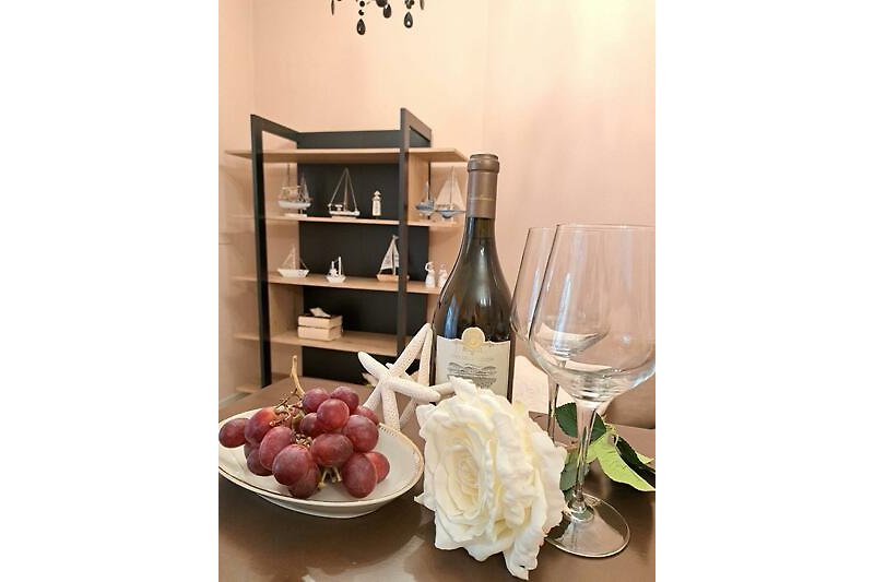 Stilvolle Tischdekoration mit Wein, Obst und Geschirr.