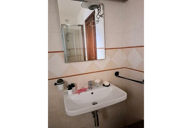 Modernes Badezimmer mit rechteckigem Spiegel und Fliesen.