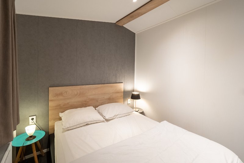 Schlafzimmer mit bequemem Bett, stilvoller Lampe und gemütlichem Holzdekor.