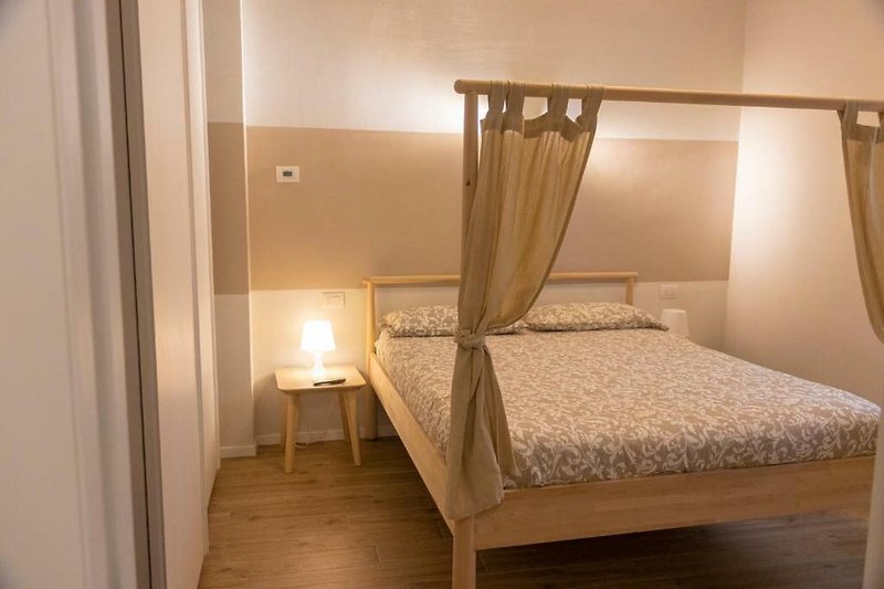 Elegantes Schlafzimmer mit Himmelbett, Holzmöbeln und Lampenschirm.