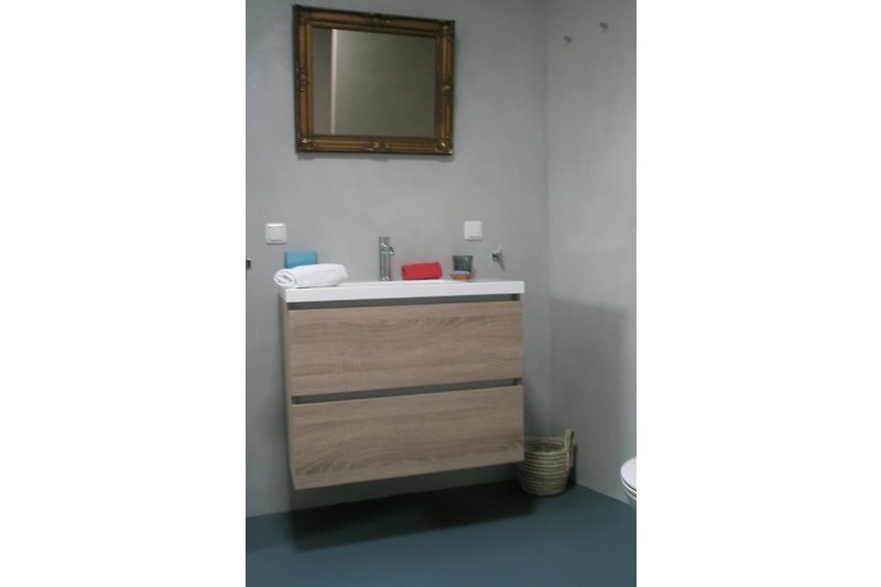 Badezimmer Waschbeckenmöbel und geheitzter Spiegel.