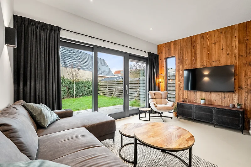 Wohnbereich mit Sofa, TV, Holzmöbeln und großzügigem Tageslicht.