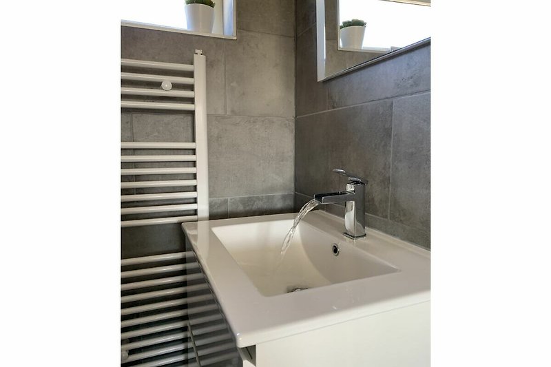 Modernes Badezimmer mit Glaswaschbecken und Metallarmatur.