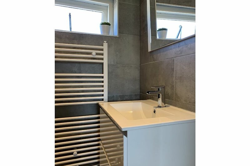 Moderne Badezimmer mit Glaswaschbecken und Metallarmatur.