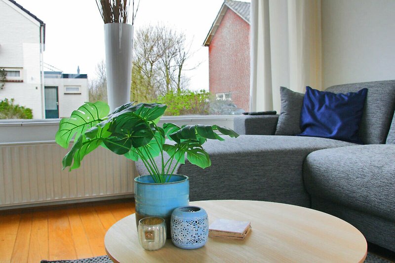 Wohnzimmer mit Pflanzen, Holzmöbeln und Tisch.