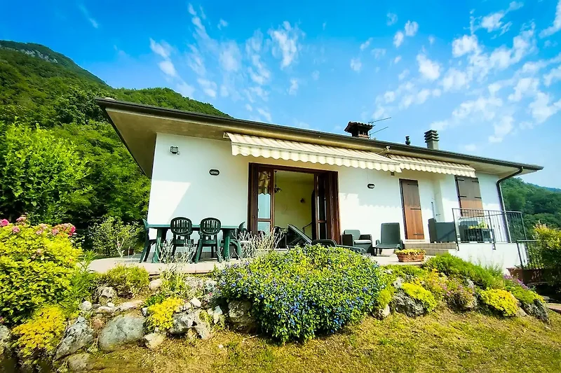 Charmantes Landhaus mit Garten, Bäumen und malerischem Bergblick.