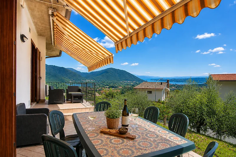 Balkon mit Outdoor-Möbeln, Sonnenschutz und Blick auf das Gebirge.