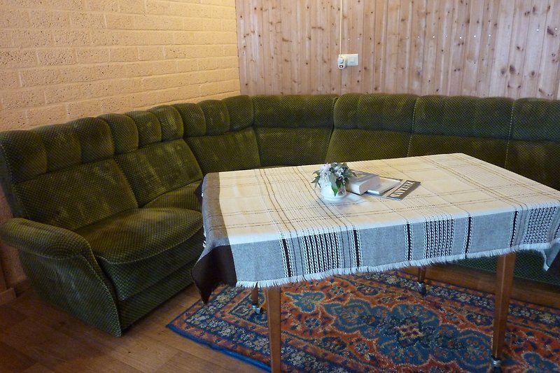 Wohnzimmer mit Tisch, Couch und Musterteppich.