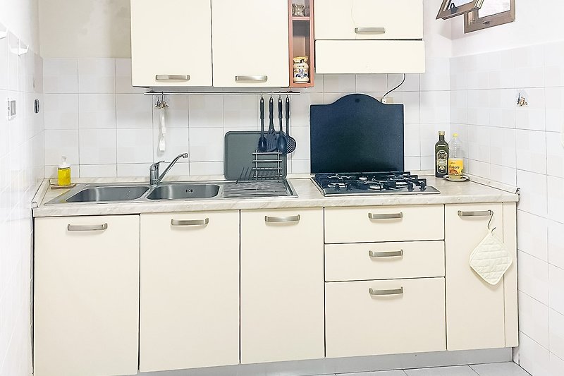 Moderne Küche mit grauen Schränken und Holztisch.