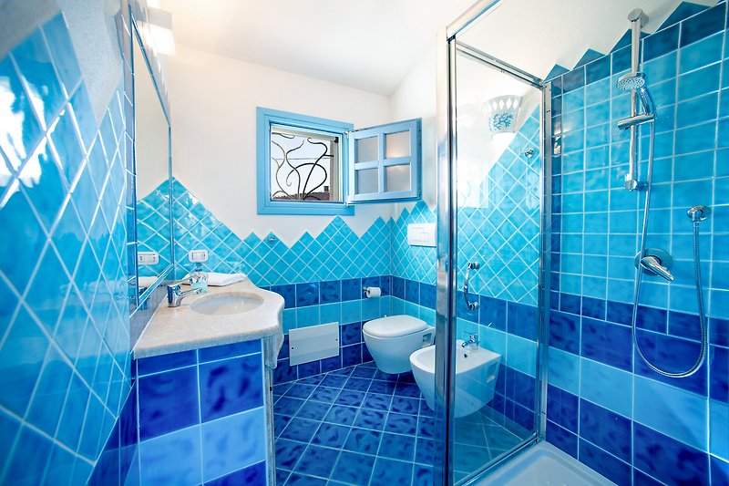Modernes Badezimmer mit blauer Dusche und Spiegel.