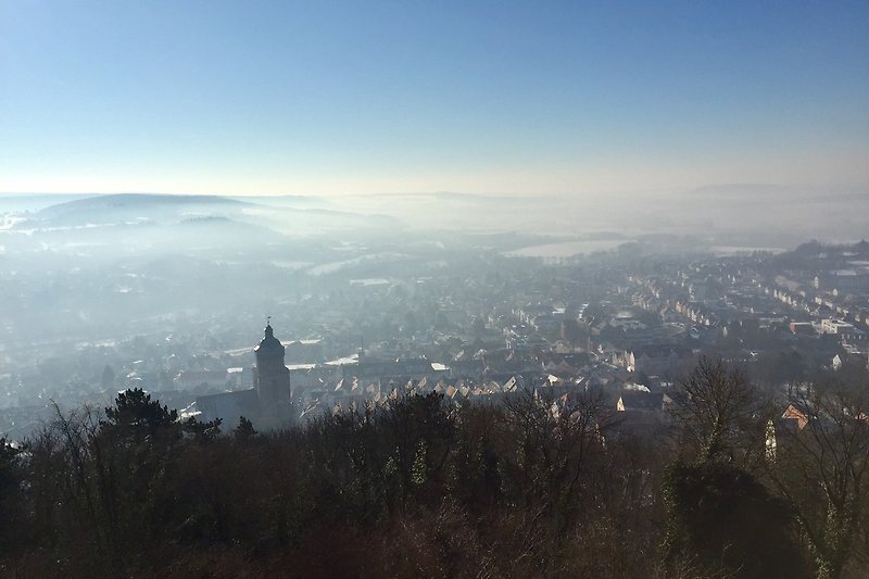 Beeindruckende Berglandschaft mit Nebel und Stadt im Hintergrund.