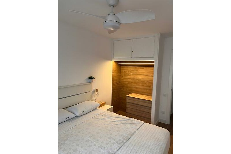 Schlafzimmer mit bequemem Bett und beleuchteten Einbauschrank