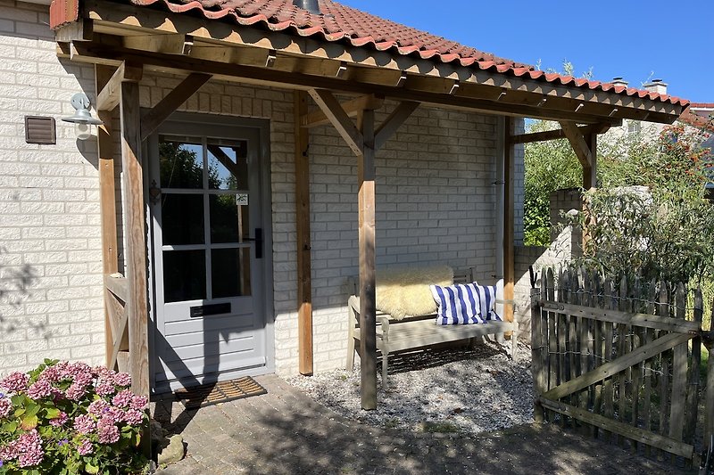 Holzveranda mit Eingang und Bank. #