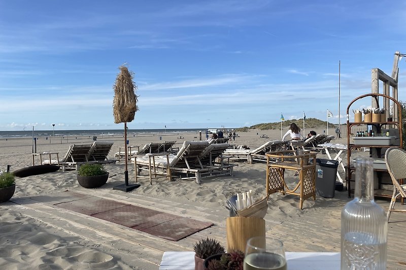 Strand mit Palmen, Stühlen, Tassen und Blick aufs Meer.